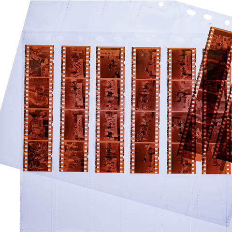 Filmnegative in Klarsichthüllen, angeordnet in Reihen, mit verschiedenen Motiven und Bildern. Einige Negative sind lose daneben.