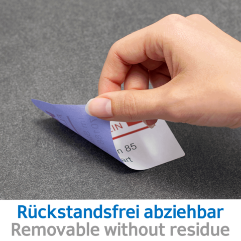 Eine Hand zieht einen abziehbaren Aufkleber von einer Oberfläche, mit dem Text „Rückstandsfrei abziehbar“ sichtbar.