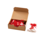 Eine offene Kartonbox mit roten und weißen Quasten, einige Quasten liegen daneben.