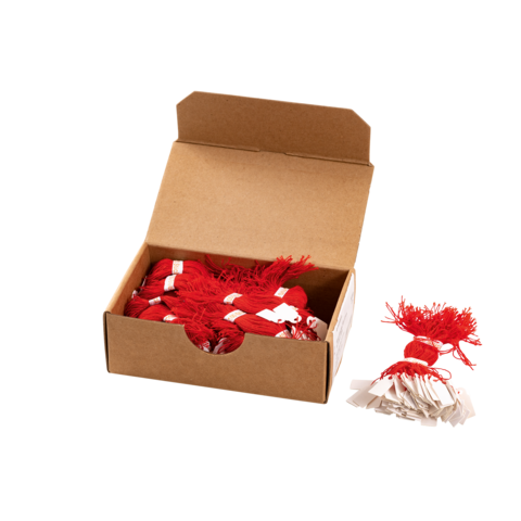 Eine offene Kartonbox mit roten und weißen Quasten, einige Quasten liegen daneben.