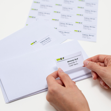 En mapp med märkta fack för inkommande och utgående dokument, bredvid kuvert och en blå penna på ett bord.