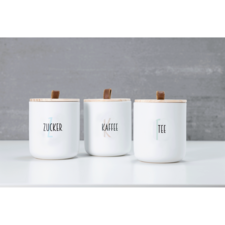 Drei weiße Behälter mit Holzdeckeln, beschriftet mit "Zucker", "Kaffee" und "Tee". Sie stehen auf einer weißen Oberfläche.