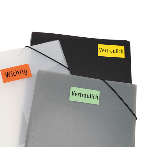 Kartonbox auf einem Tisch, mit einem roten Heftchen oben und einem grünen "TOP"-Schild. Im Hintergrund sind Bücherregale sichtbar.