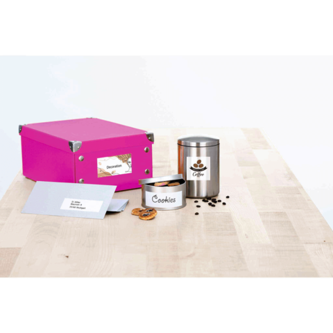Bunte Box mit Aufkleber "Dekoration", Keksdose mit Aufschrift "Cookies" und Kaffeetasse auf einem Holztisch.