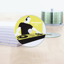 CD med titeln 'Greatest Hits' och en DJ-design, omgiven av transparenta CD-fodral på ett bord.
