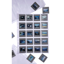 Eine Sammlung von Diapositive in einer durchsichtigen Hülle, mit mehreren einzelnen Dias, die um die Hülle herum angeordnet sind.