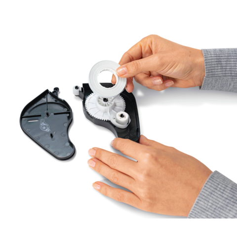 Eine Hand hält eine transparente Rolle, die in ein schwarzes Gehäuse eingesetzt wird, während das Gehäuse teilweise geöffnet ist.