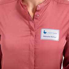 Ein Namensschild an einer blauen Bluse zeigt den Namen "Linda Miller" und die Position "Marketing" für die Agentur Print Media.