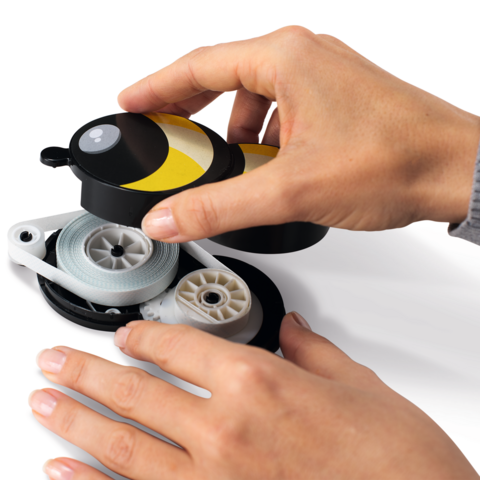 En hand håller en gul och svart rulle, medan en annan hand drar ut snöret.