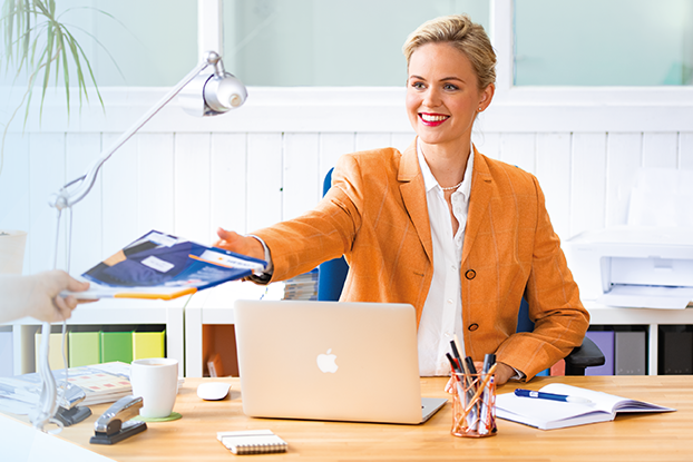 Två personer vid ett bord som presenterar etiketter. Till vänster en man med etikettblad, till höger en kvinna med en laptop och etiketter.