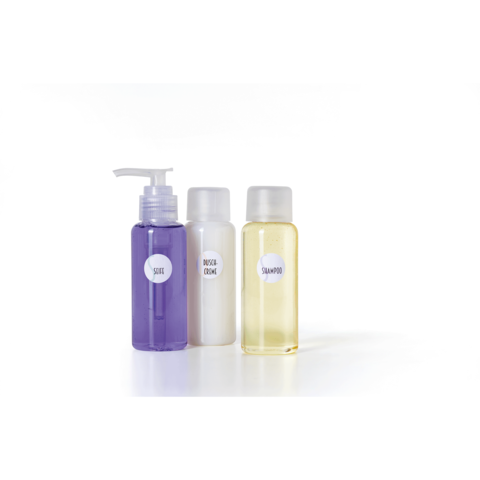 Drei Flaschen mit Pflegeprodukten: eine lila Flasche mit Pumpe, eine weiße Flasche und eine gelbe Flasche, beschriftet mit "Shampoo" und "Dusche Creme".